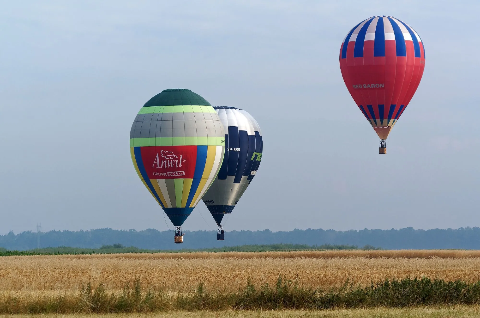 Trzy balony na ogrzane powietrze nad polem zboża